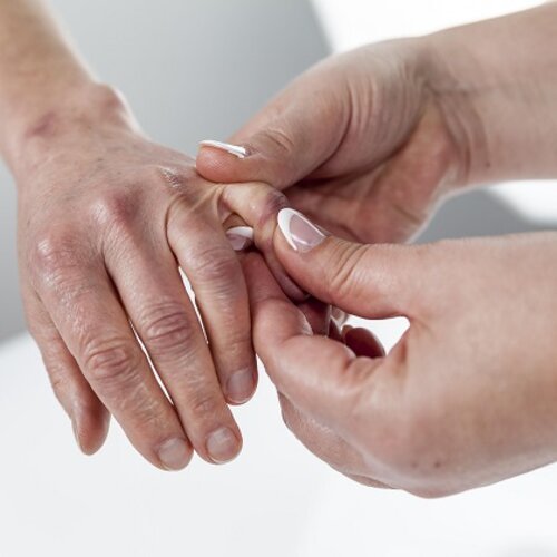 Ergotherapeutin behandelt die Hand einer Patientin